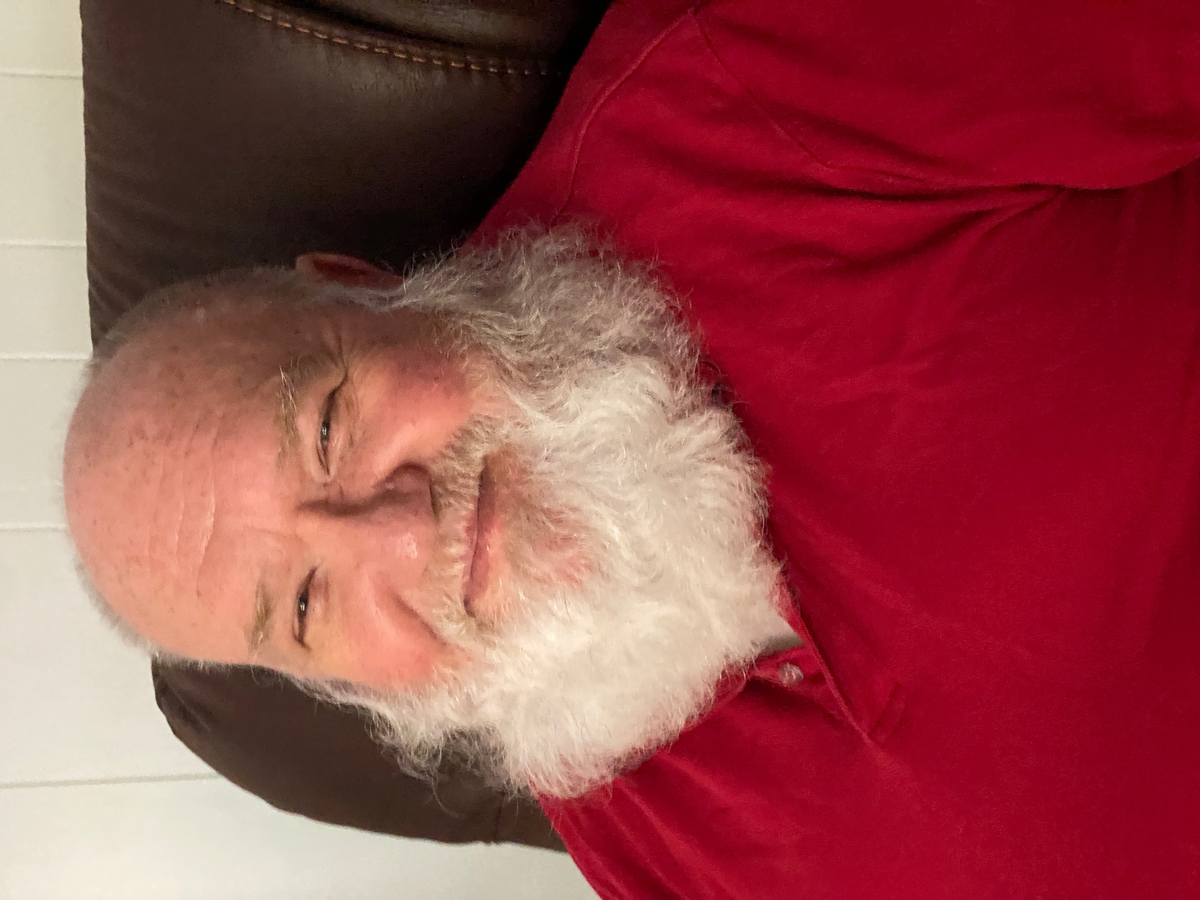 Michael out of costume in a red shirt, smiling, with his full white beard